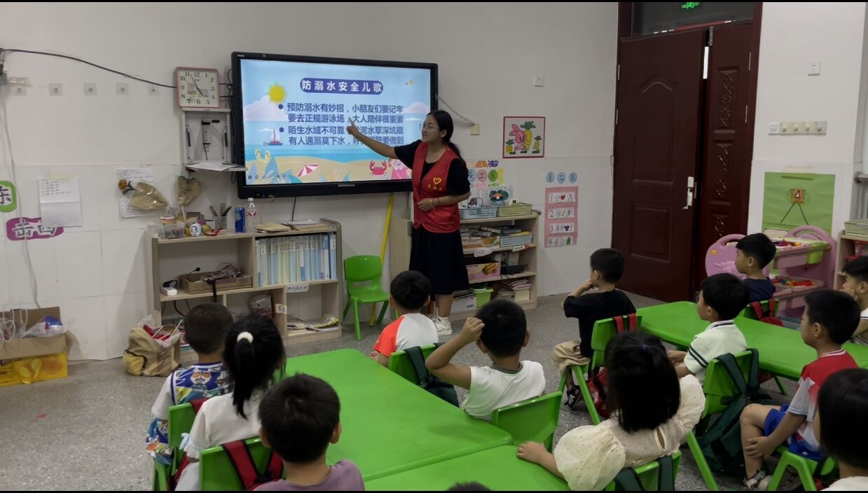 图为实践队员带领小朋友朗读防溺水安全儿歌